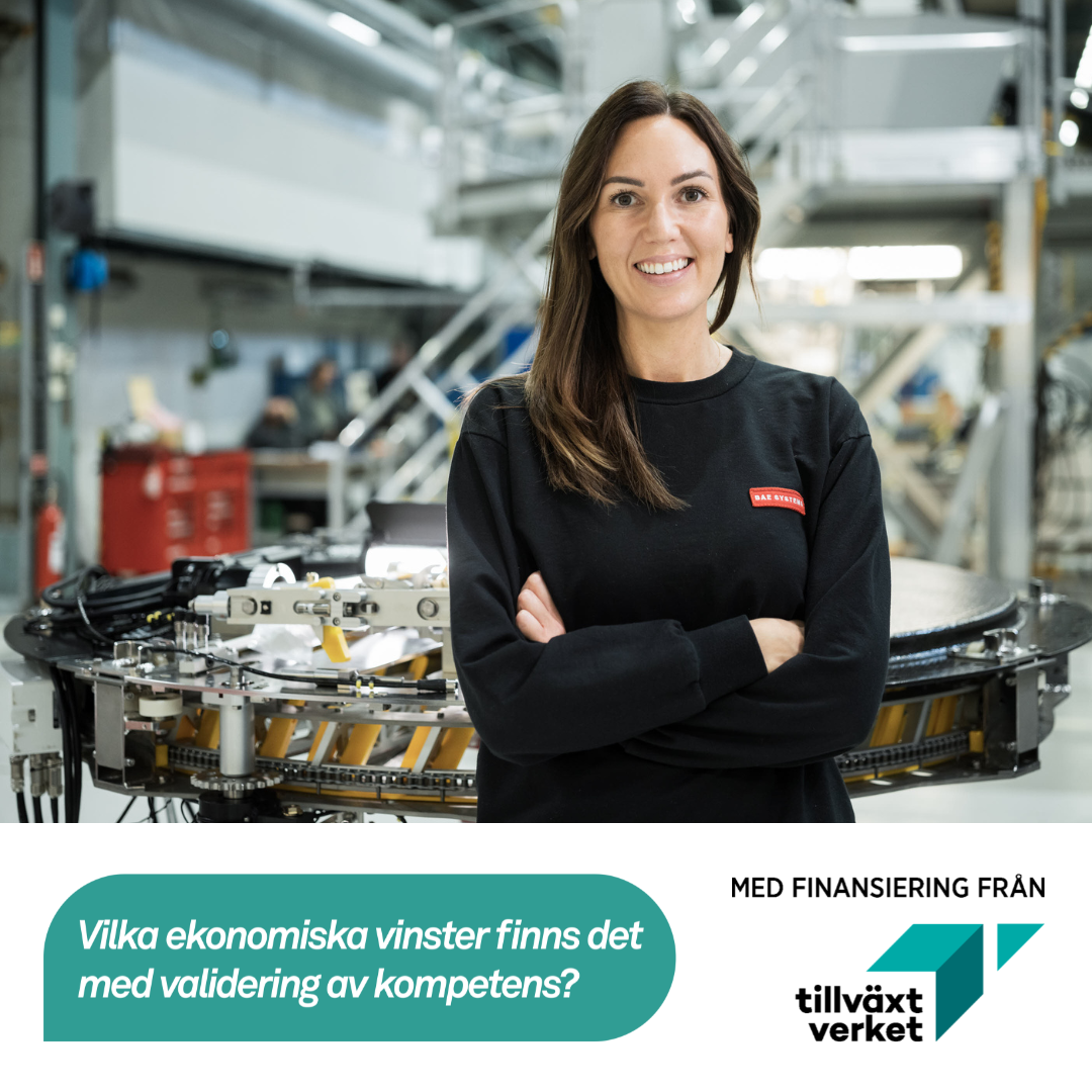 Kvinna i 30 års ålder, står i arbetskläder, i BAE Systems lokaler, ler mot kameran.