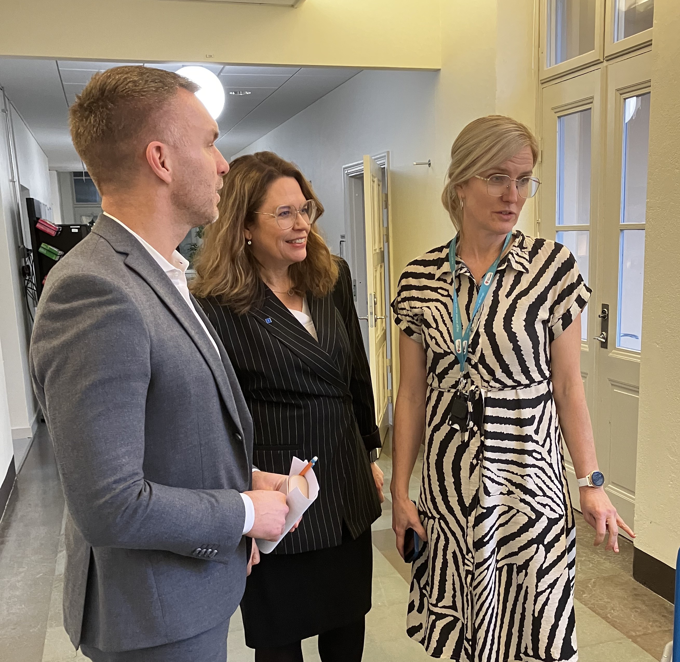 En man och två kvinnor står i en korridor och samtalar.