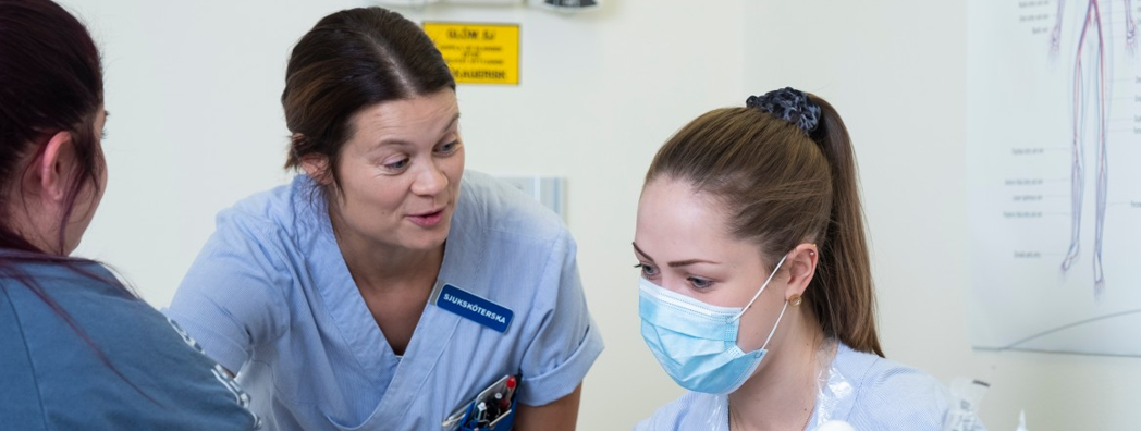 Två sjuksköterskor pratar med en patient. 