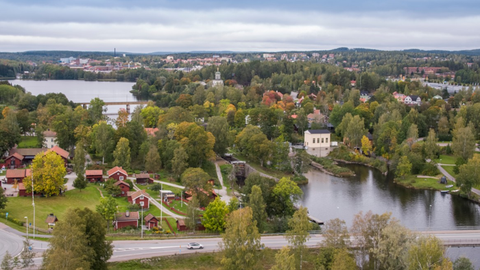 Flygbild där man ser båda skog, vattendrag, hus och trottoarer.