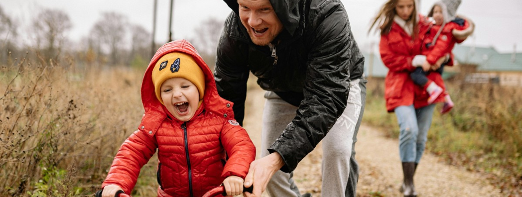 En barnfamilj är ute och leker i regnet