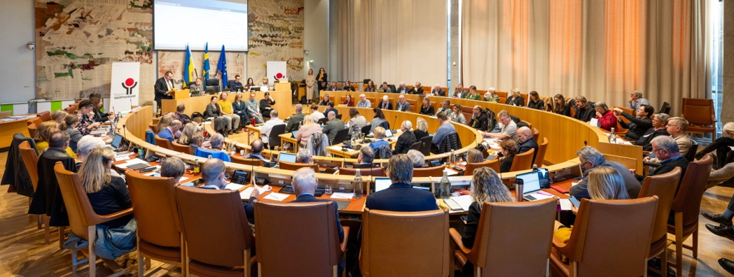 Stor sammanträdeslokal med människor.