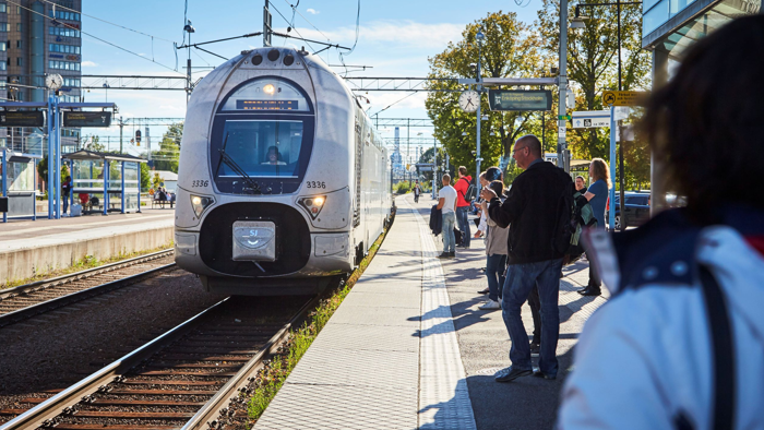 Människor står på perrongen och väntar på tåget som precis kommer in.