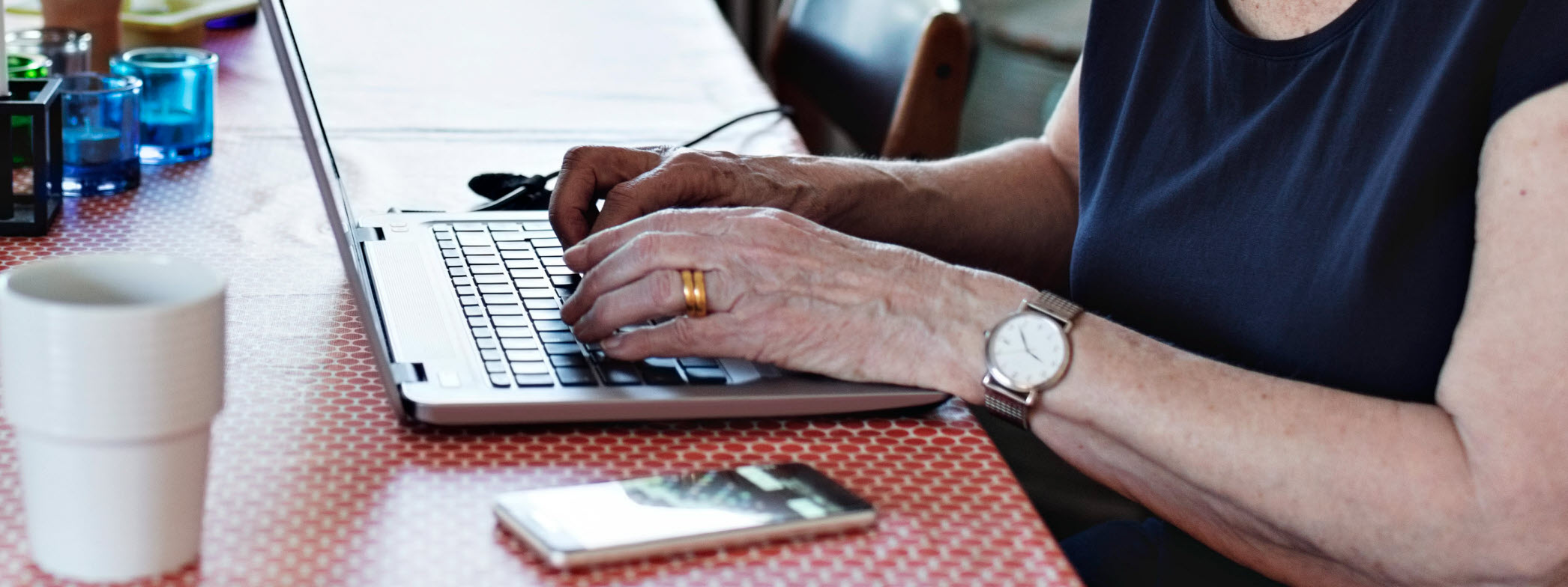 Äldre kvinna skriver på tangentbordet på en bärbar dator.
