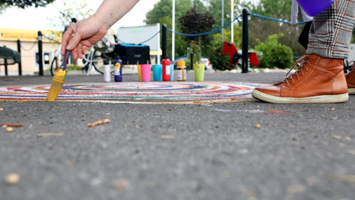 En person målar ett konstverk på asfalten