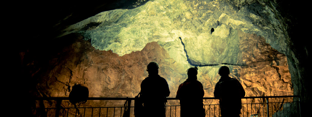 Silhuetter av tre människor vid staket i gruva