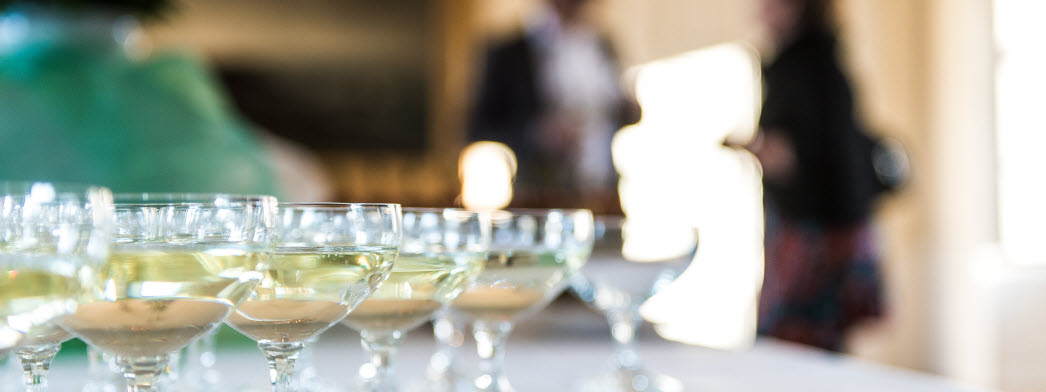 Champagneglas står på ett bord, människor minglar i bakgrunden