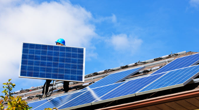 En person installerar solenergi på tak