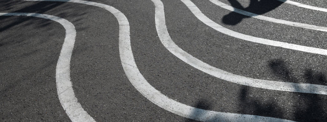 En asfalterad väg med vita vågiga vägmarkeringar