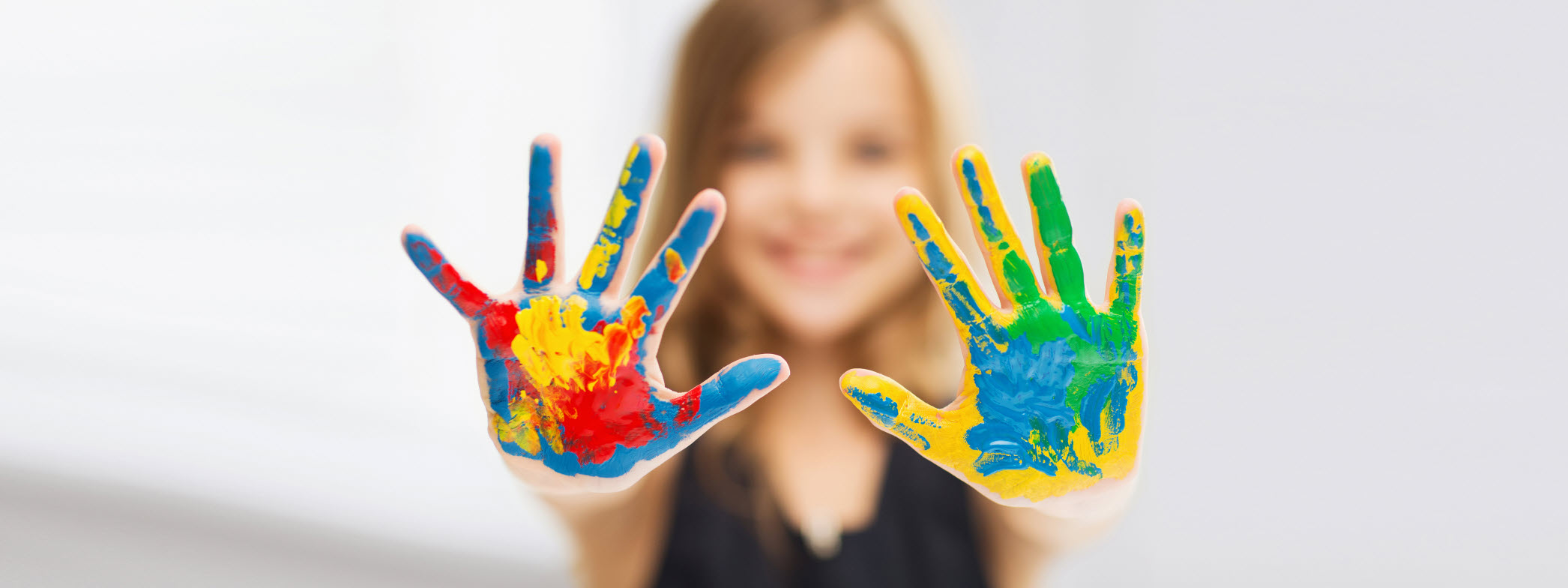 En tjej visar upp sina händer som är fulla med färg.